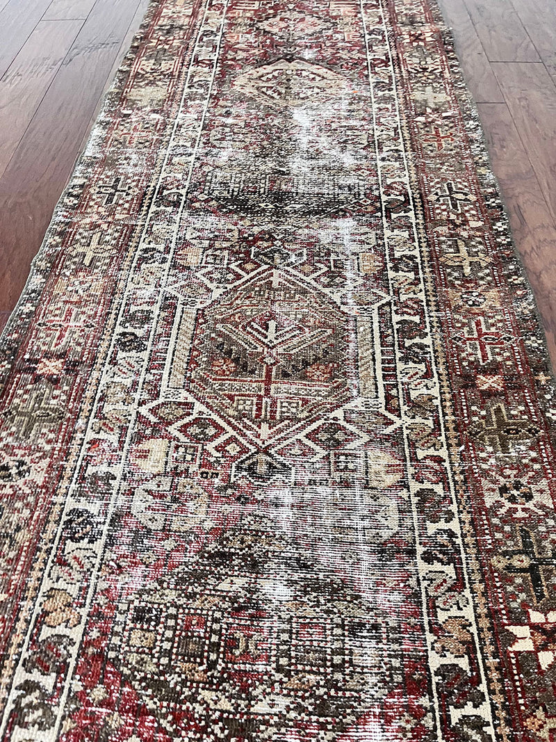 an antique heriz karajah runner with a deep wine red and brown palette and light pink and yellow accents