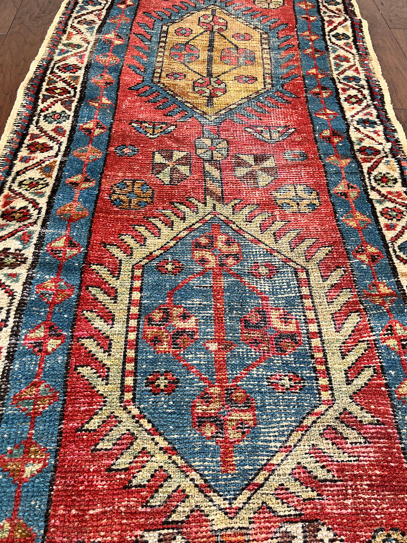 an antique heriz runner with a red field and blue, green and mustard medallions