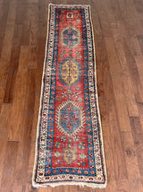 an antique heriz runner with a red field and blue, green and mustard medallions