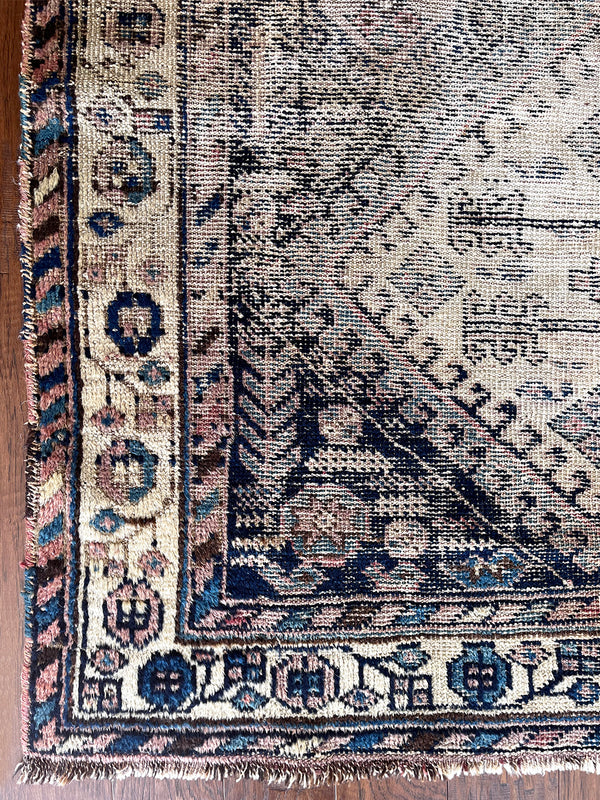 an antique afshar rug with a dark blue and ivory palette and pretty coral accents