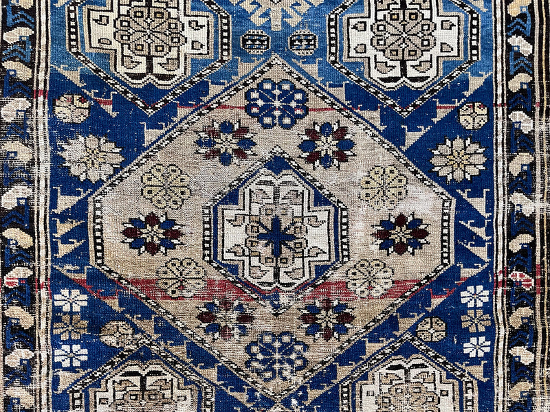 an antique caucasian shirwan rug with an electric blue field and taupe medallions