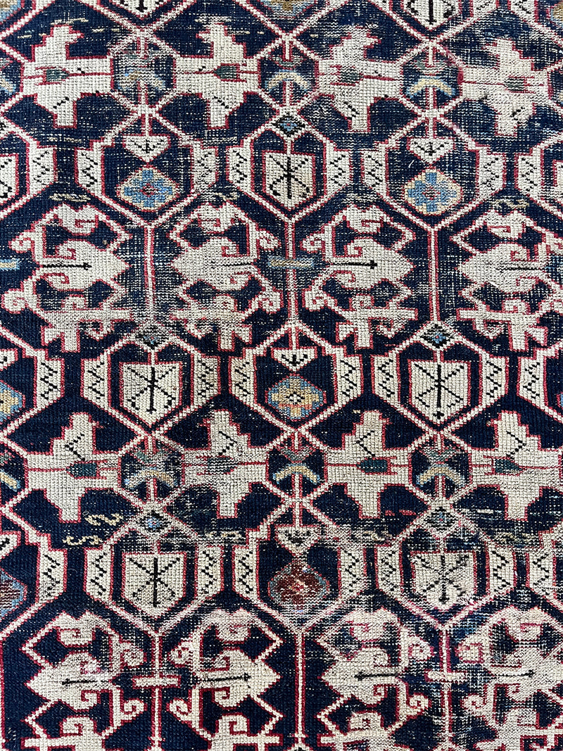 an antique caucasian shirwan rug with a dark blue field and a geometric pattern in cream