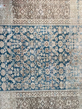 a wide persian runner with a cream and brown border and a blue floral field