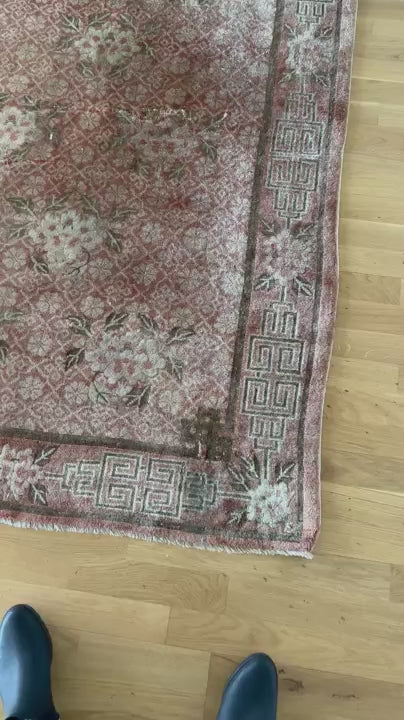 an antique chinese peking rug with blush tones and floral accents