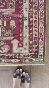 An antique turkish prayer rug with dark red field and light cream and yellow accents