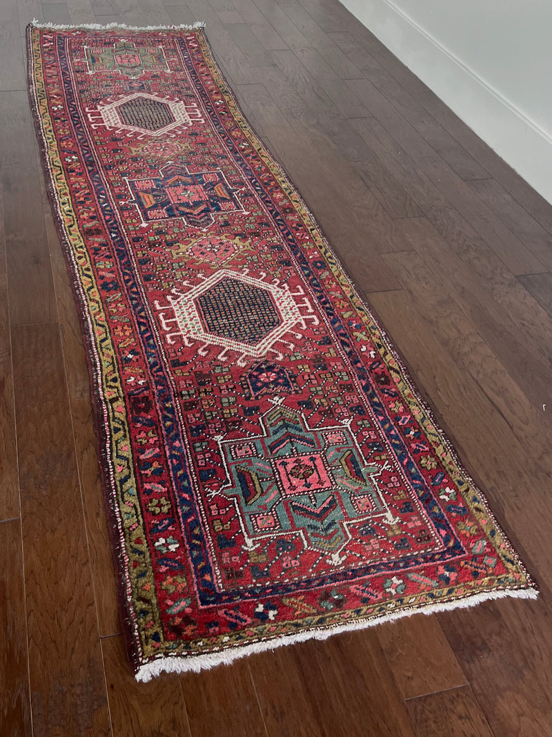 a vintage heriz runner with turquoise and hot pink accents on a red field