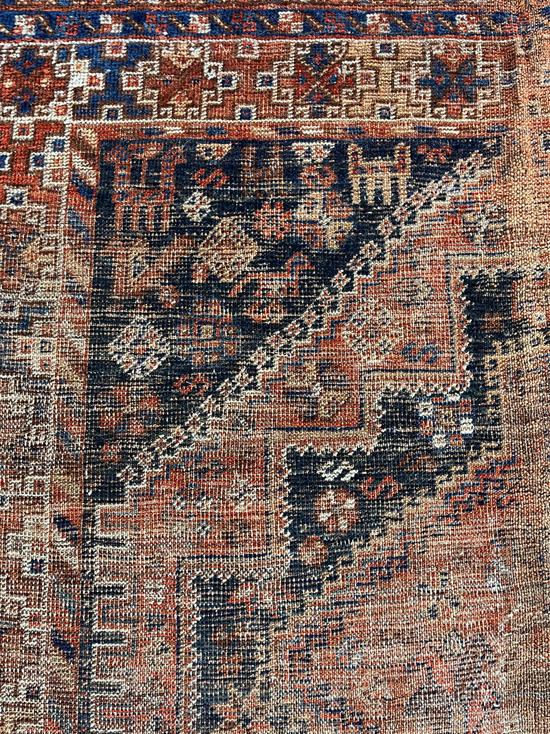 an antique qashqai rug with black and brick red accents