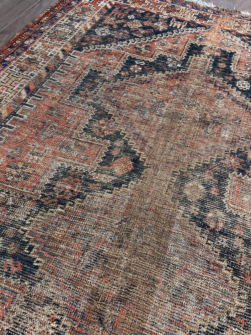 an antique qashqai rug with black and brick red accents