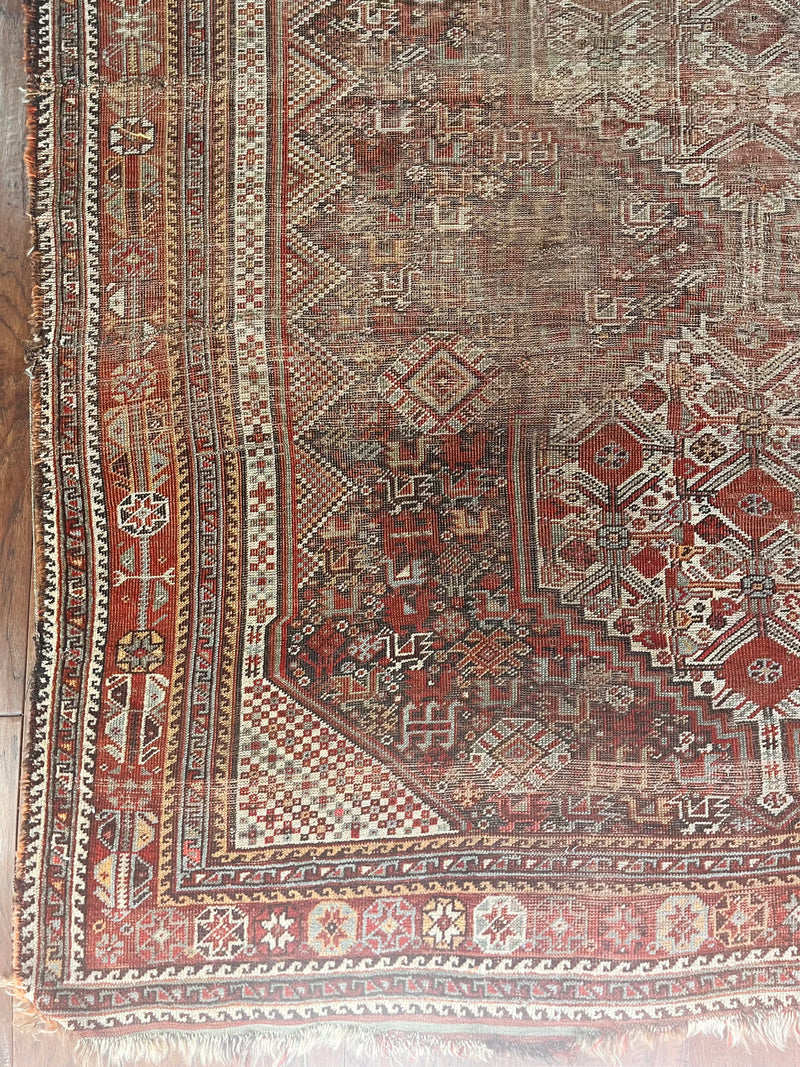 an earthy toned antique shiraz rug with 3 cream medallions