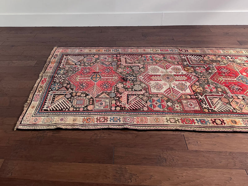 an antique caucasian runner with a taupe field and hot pink medallions 
