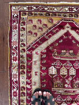 An antique turkish prayer rug with dark red field and light cream and yellow accents