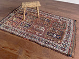 an antique khamseh rug with an earthy palette and an oversized paisley design
