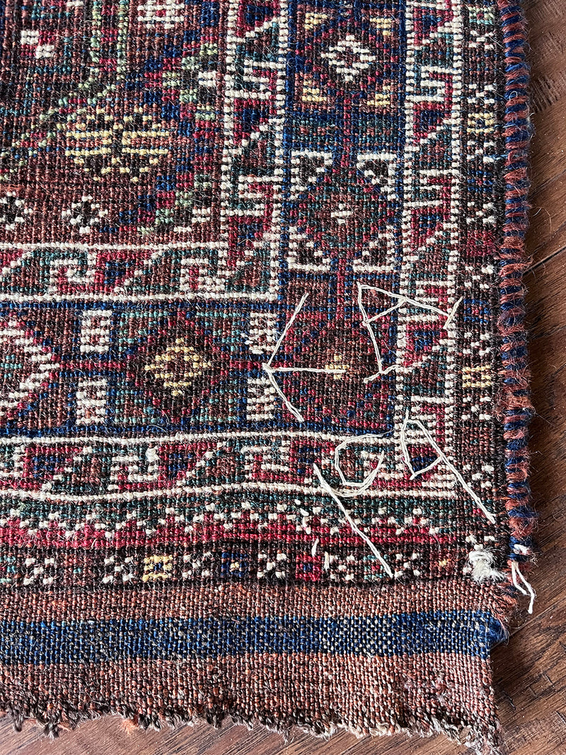 an antique khamseh rug with an earthy palette and an oversized paisley design