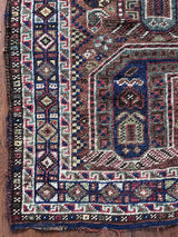 an antique khamseh rug with an earthy palette and an oversized paisley design