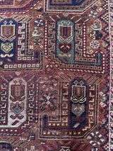 an antique khamseh rug with an earthy palette and an oversized paisley design
