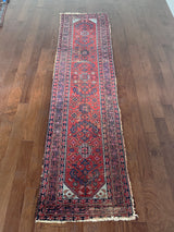 an antique malayer runner with a red field and blue floral accents