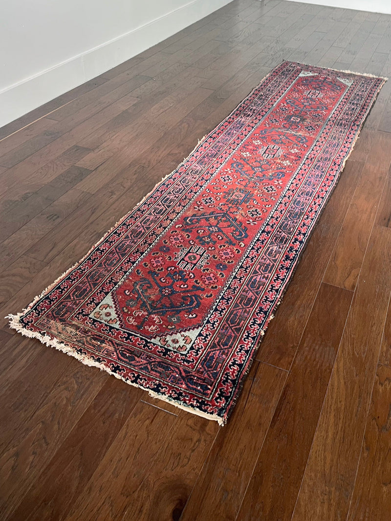 an antique malayer runner with a red field and blue floral accents