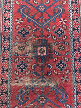 an antique malayer runner with a red field and blue floral accents