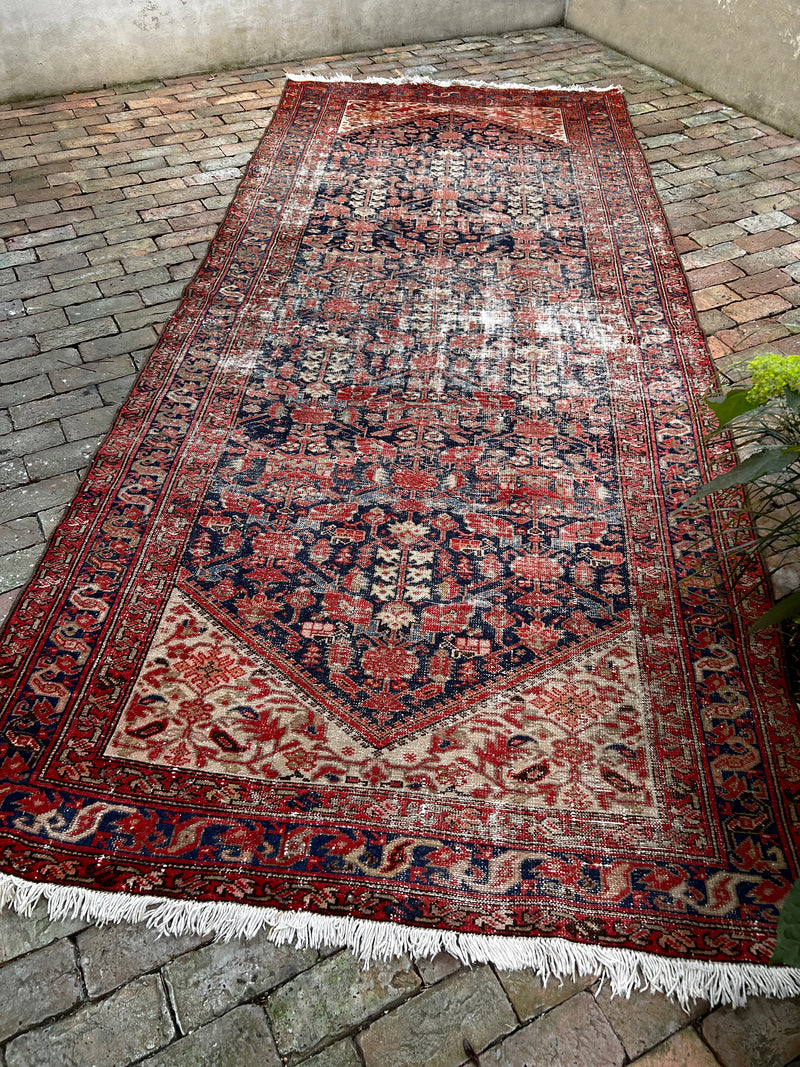 a vintage malayer rug with an indigo field and bright neon pink and red floral accents
