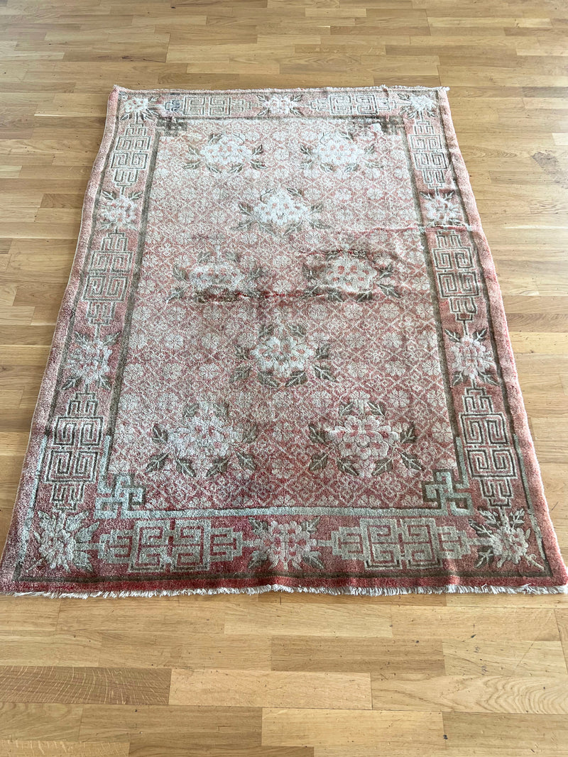 an antique chinese peking rug with blush tones and floral accents