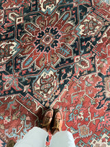 an antique heriz rug with a rusty red field and large navy blue medallion
