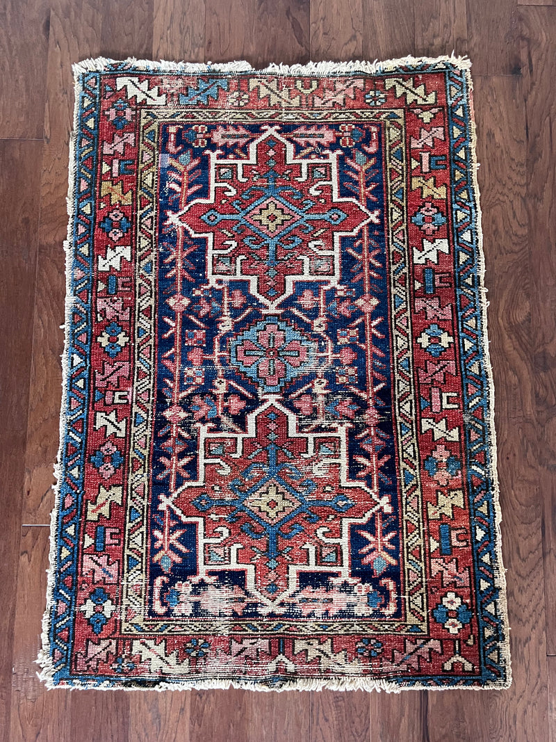 An antique Heriz rug with a blue and brick red palette. 