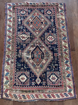 an antique caucasian shirwan rug with a midnight blue field and brick red accents