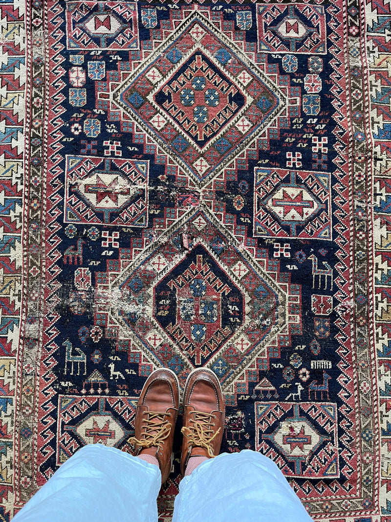 an antique caucasian shirwan rug with a midnight blue field and brick red accents