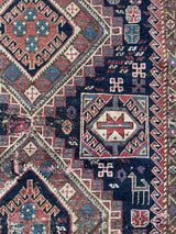 an antique caucasian shirwan rug with a midnight blue field and brick red accents