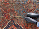 a large antique qashqai rug with a terracotta field and blue accents