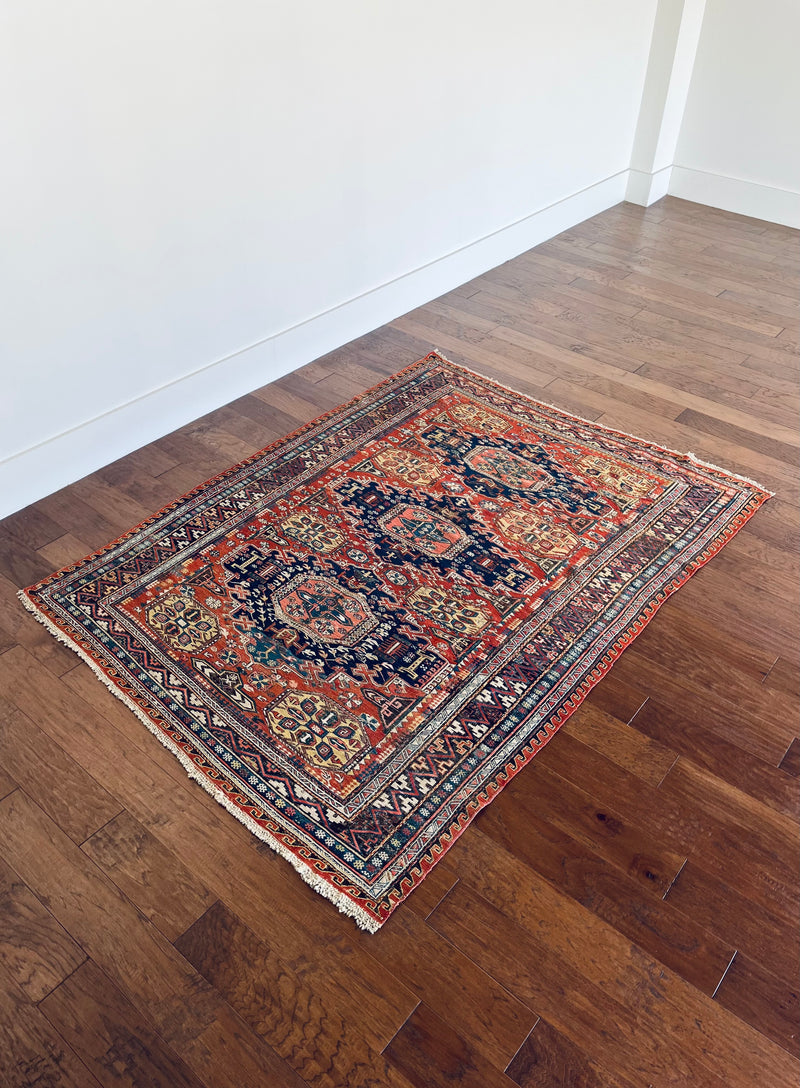 a medium-sized caucasian sumac rug with a red field, 3 royal blue medallions and light yellow accents
