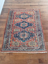 a medium-sized caucasian sumac rug with a red field, 3 royal blue medallions and light yellow accents