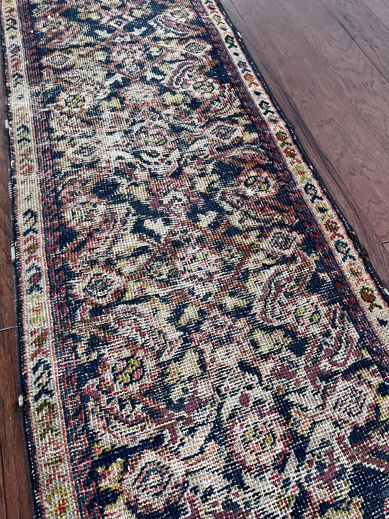 a skinny antique farahan runner with a blue field and a pink floral design