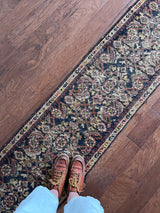 a skinny antique farahan runner with a blue field and a pink floral design