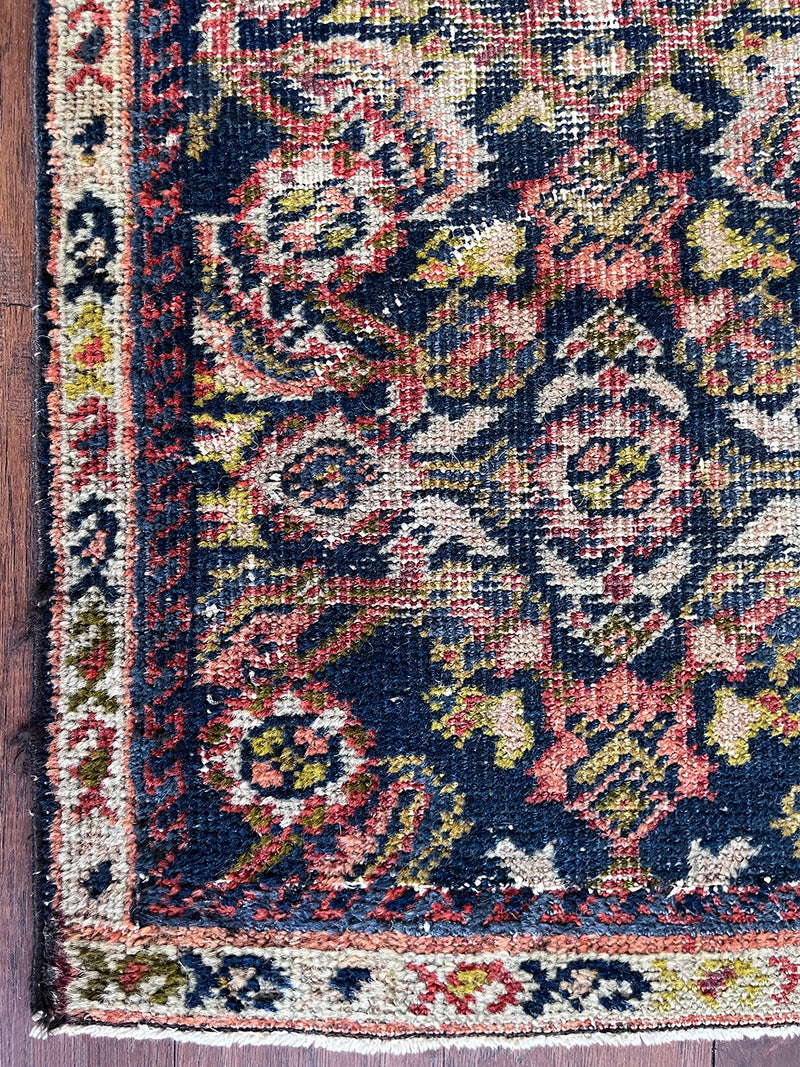 a skinny antique farahan runner with a blue field and a pink floral design