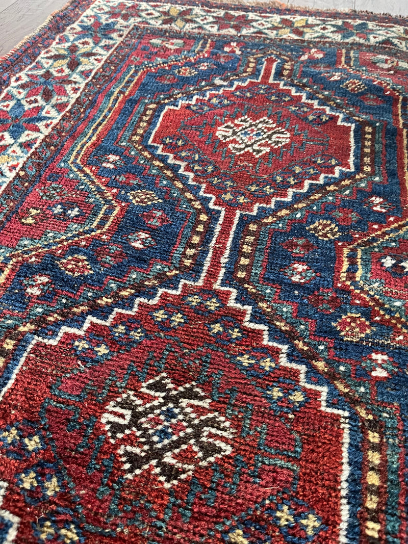 a mini antique shiraz rug with a classic red and blue palette