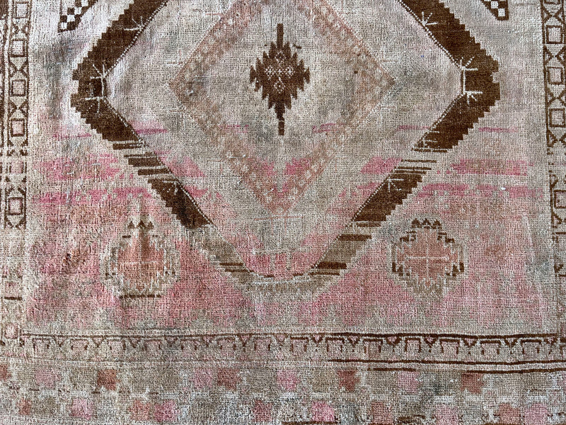 an antique turkish rug with brown and pink accents