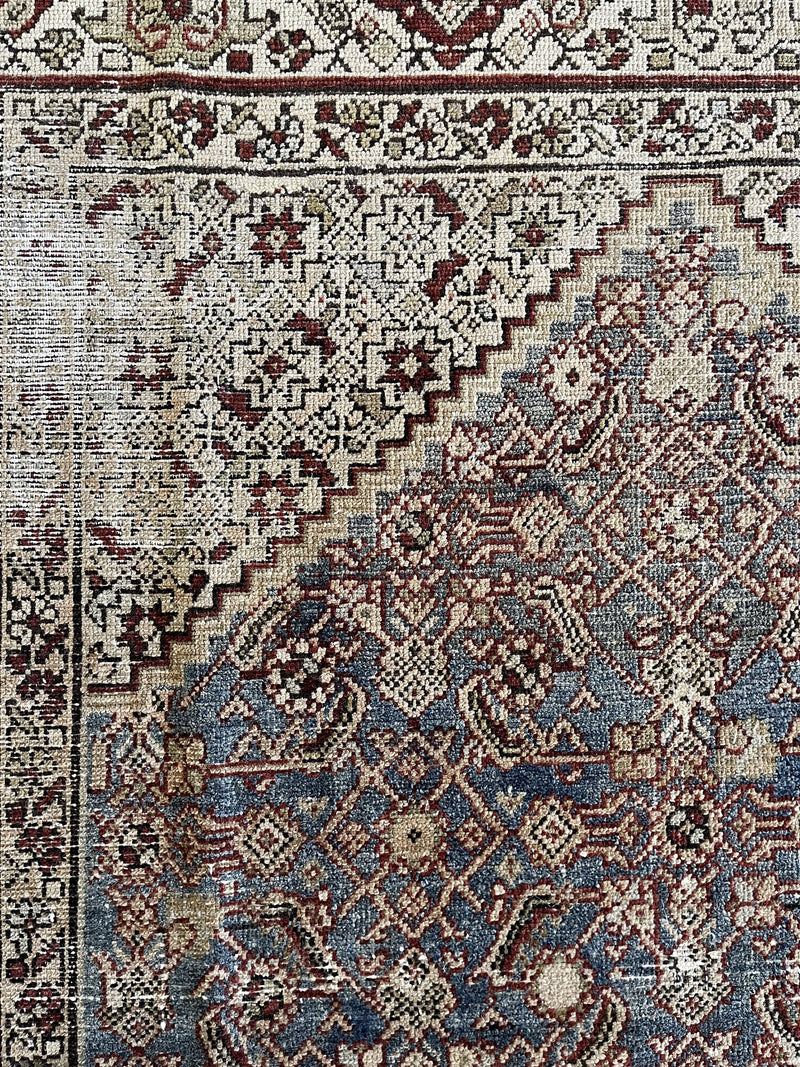 an antique Malayer rug with blue palette and cream floral details