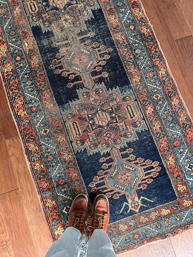 an antique runner with a dark blue field and beautiful brick red accents