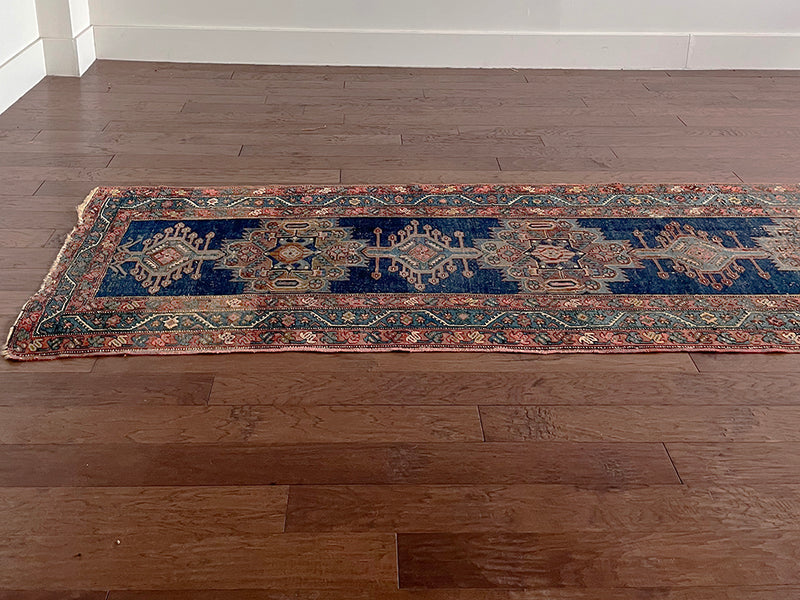 an antique runner with a dark blue field and beautiful brick red accents