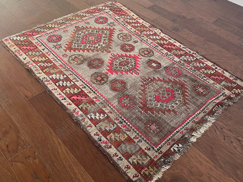 an antique north west persian rug with hot pink accents and a taupe / grey field