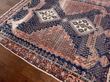 A vintage Afshar rug with a coral field and paisley on a navy background.