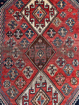 an antique qashqai rug with a red and blue palette and large central medallion