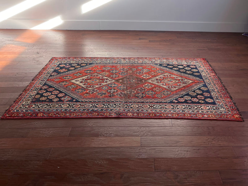 an antique qashqai rug with a red and blue palette and large central medallion