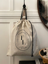a drawstring linen bag with printed frances loom logo