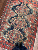 an antique afshar rug with a navy blue field and red accents