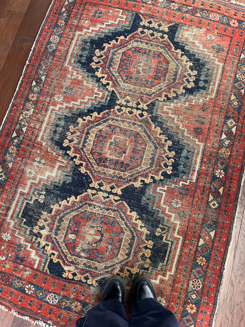 an antique afshar rug with a navy blue field and red accents