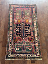 a vintage caucasian rug with a hot pink field and green accents