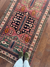 a vintage caucasian rug with a hot pink field and green accents