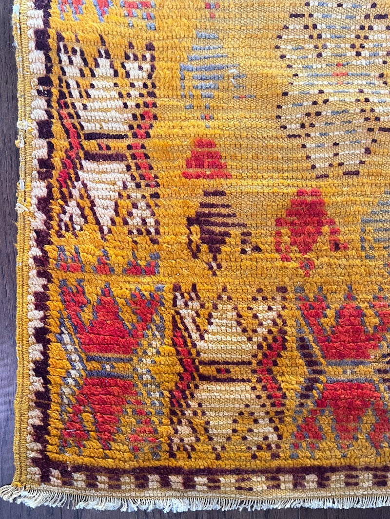 an antique moroccan rug with yellow tones and bright red accents